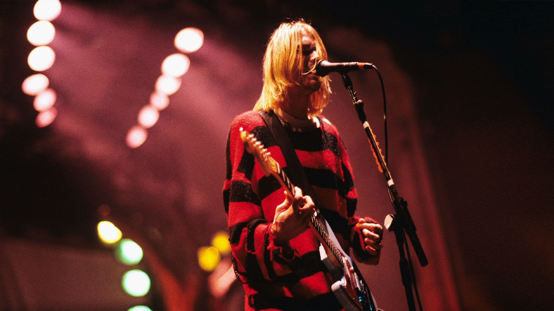 El frontman Kurt Cobain cantando en un concierto con luces rojas